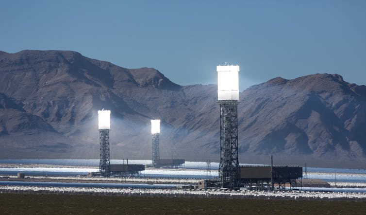 Tres torres solares resplandecientes en el desierto.