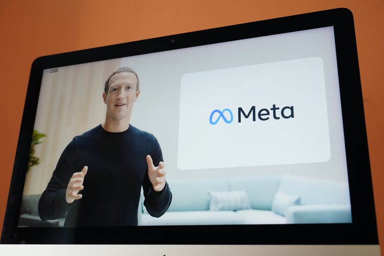 Una pantalla que muestra a Mark Zuckerberg y el nuevo logotipo de Meta
