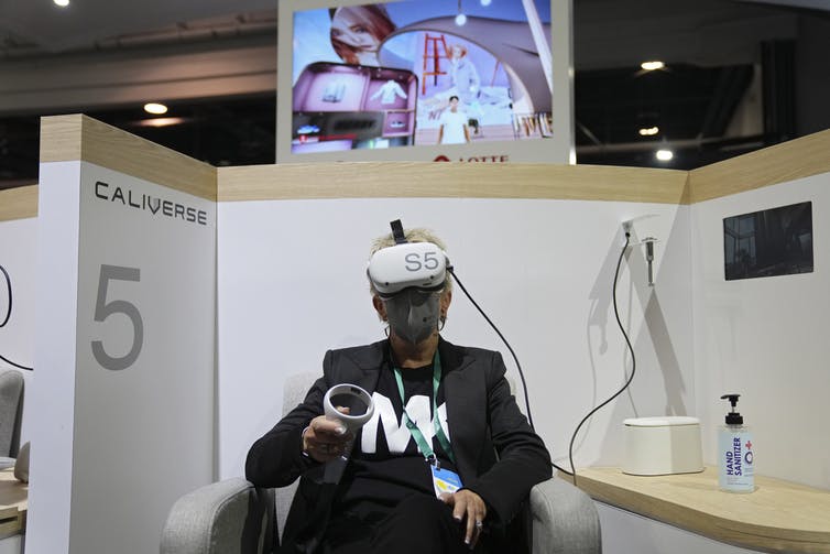Una mujer con gafas de realidad virtual se sienta en un stand de feria
