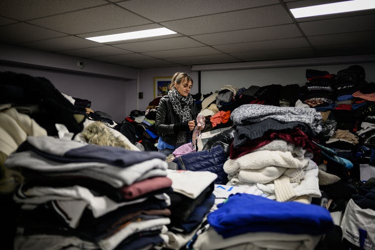 Un voluntario cuida montones de ropa donada.
