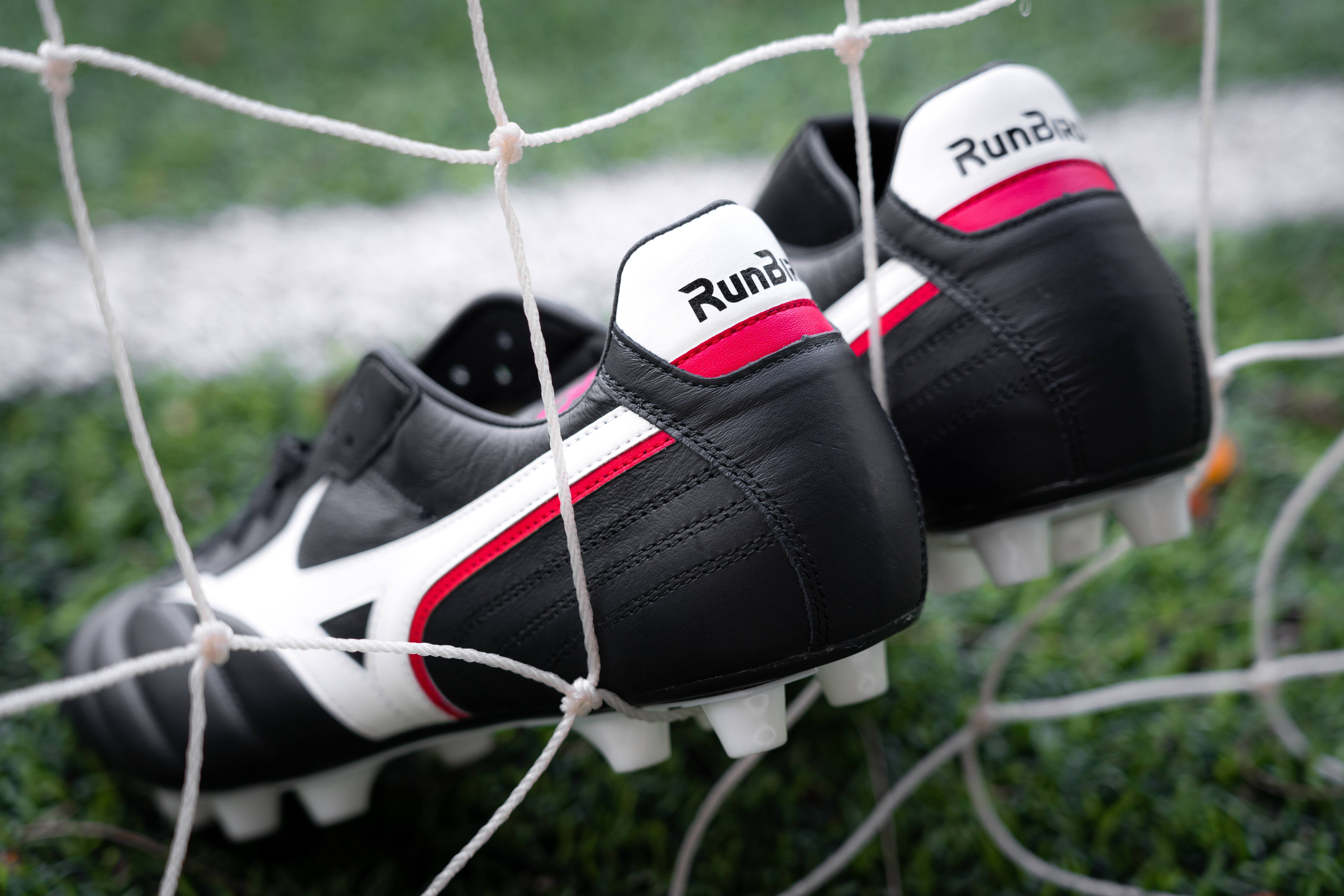 Un par de botas de fútbol descansan sobre la red interior de una portería en un campo de fútbol o de fútbol.