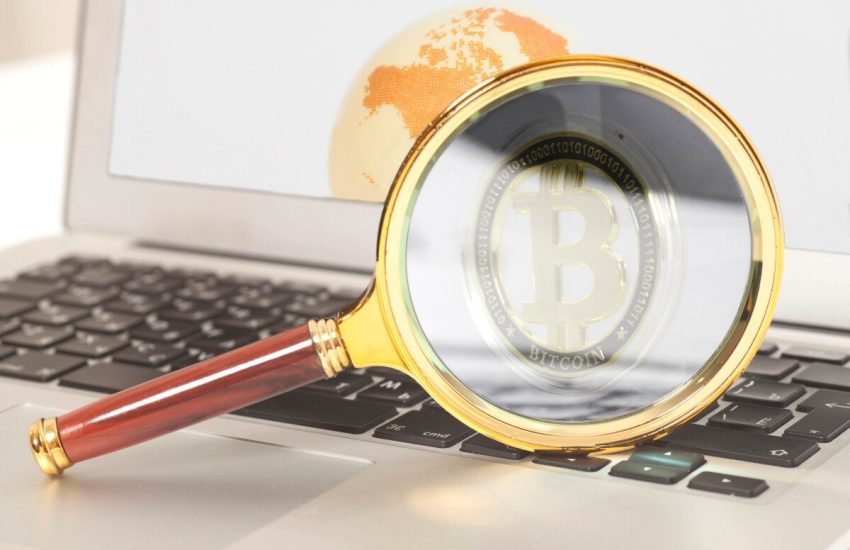 A magnifying glass focuses on a Bitcoin logo on a laptop PC&rsquo;s screen.