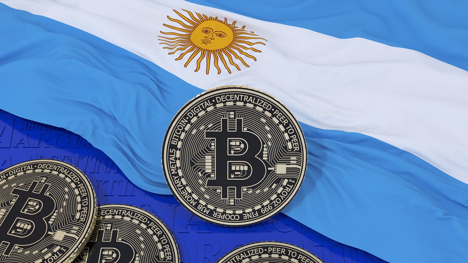 Varias monedas de metal destinadas a representar tokens de Bitcoin descansan sobre la bandera argentina.