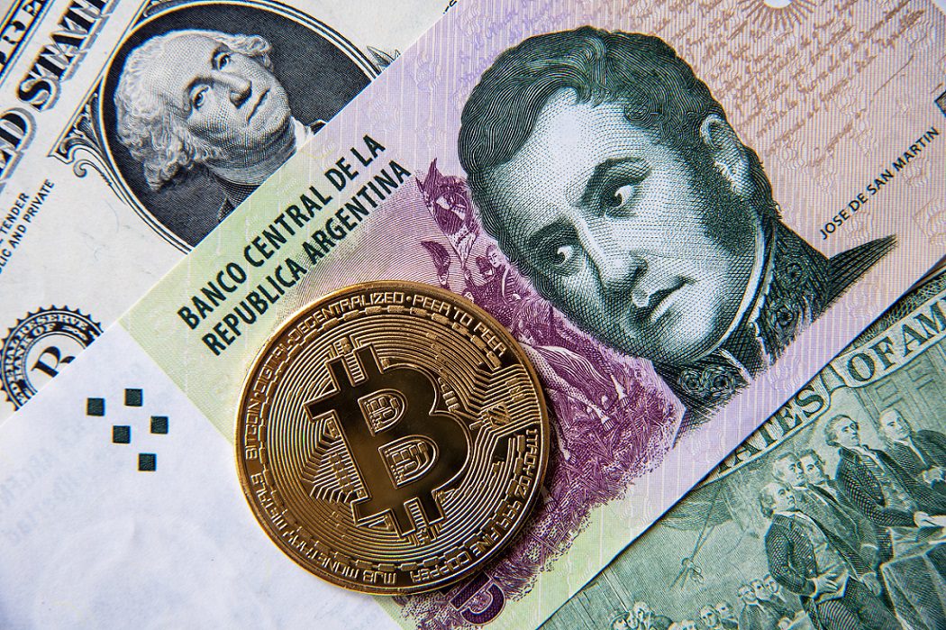 Un token de metal destinado a representar Bitcoin en la parte superior de los billetes de peso argentino y dólar estadounidense.