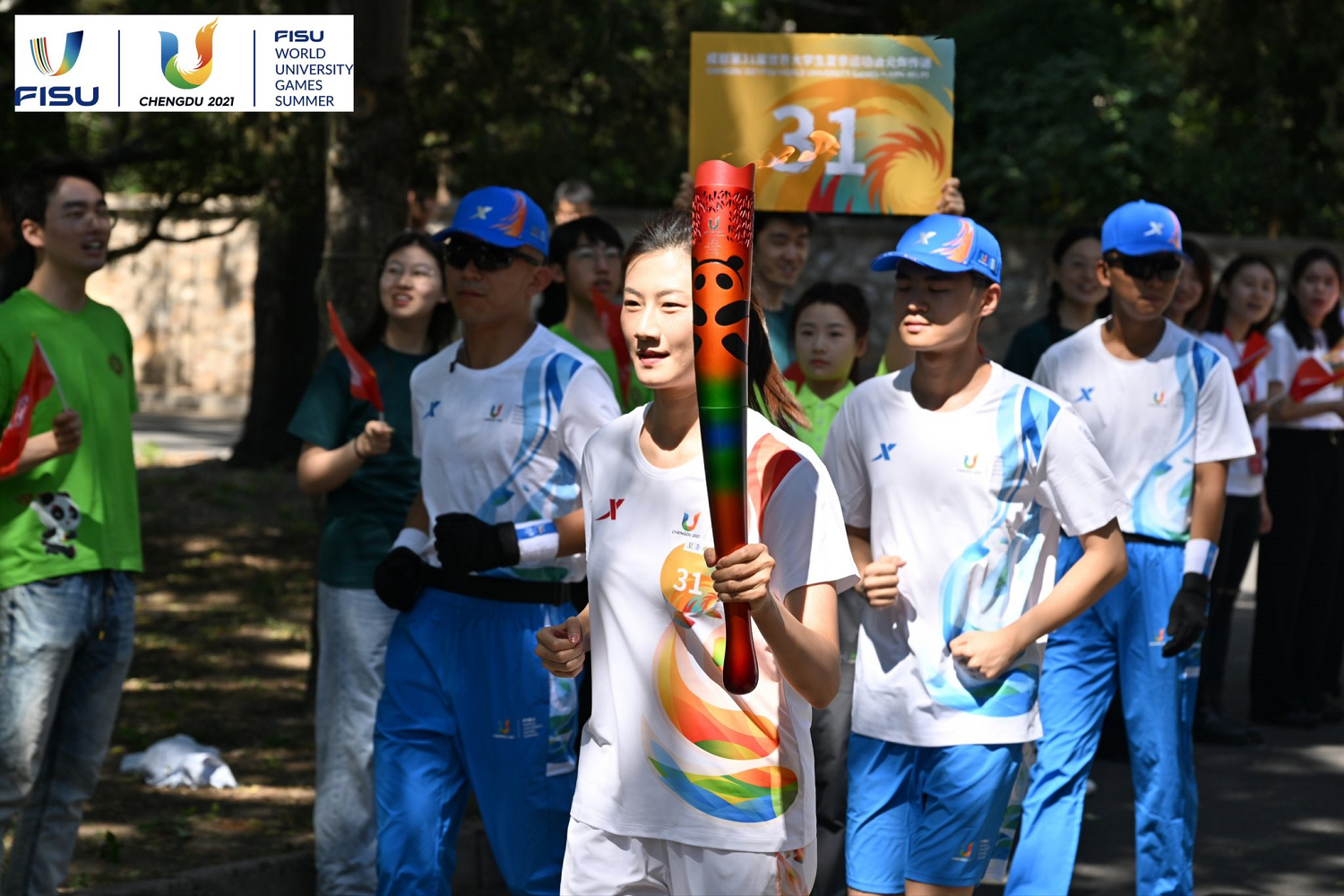         Un estudiante chino lleva la antorcha de los Juegos Mundiales Universitarios de Verano y corre por una calle arbolada de la ciudad.