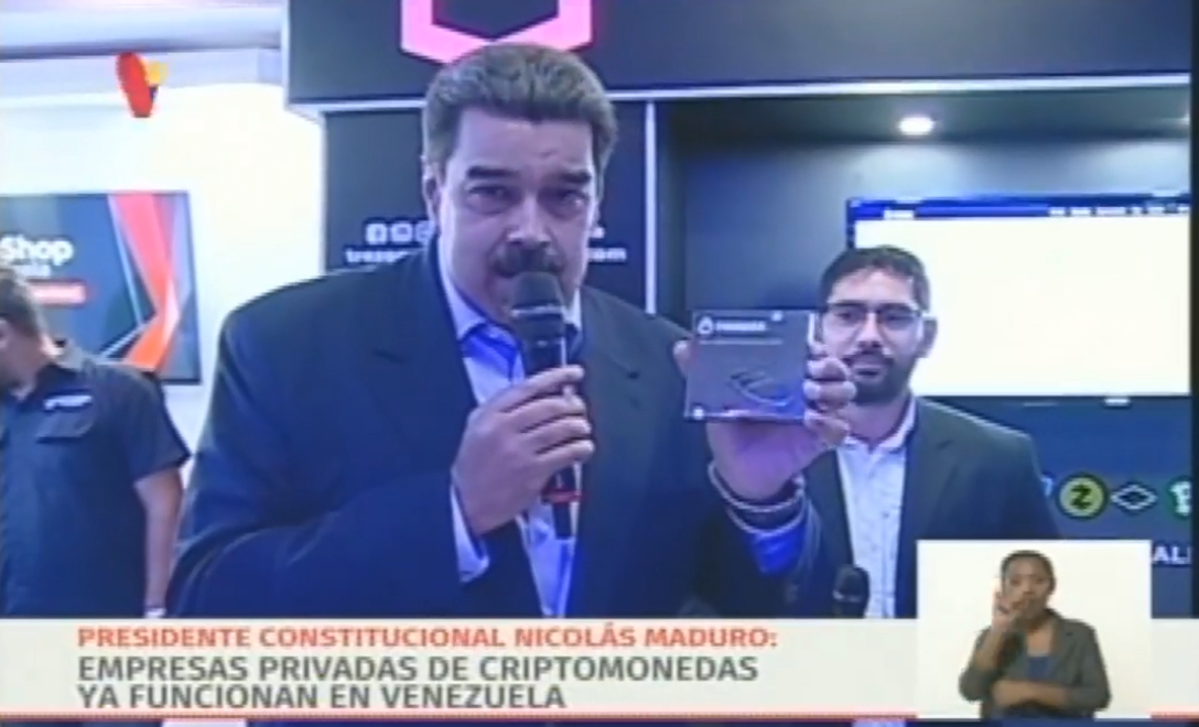 El presidente de Venezuela, Nicolás Maduro, sostiene una billetera de hardware criptográfico y habla por un micrófono.