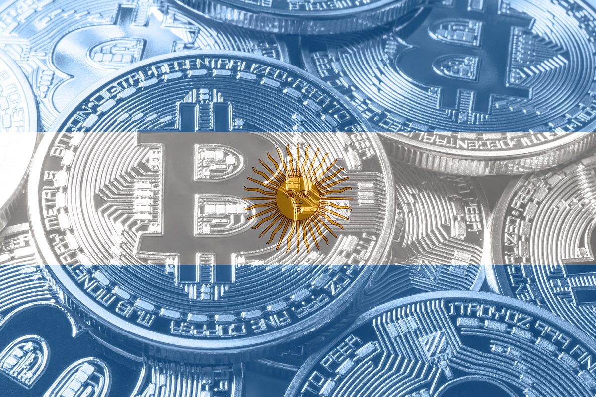 Una pila de monedas de metal destinadas a representar Bitcoin superpuestas a una imagen de la bandera de Argentina.