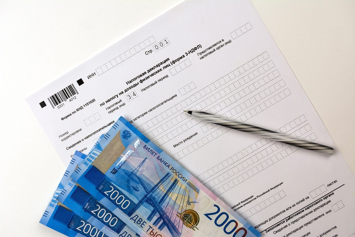 Sobre una mesa hay una copia en blanco del formulario de declaración de impuestos ruso, billetes de rublos y un bolígrafo.