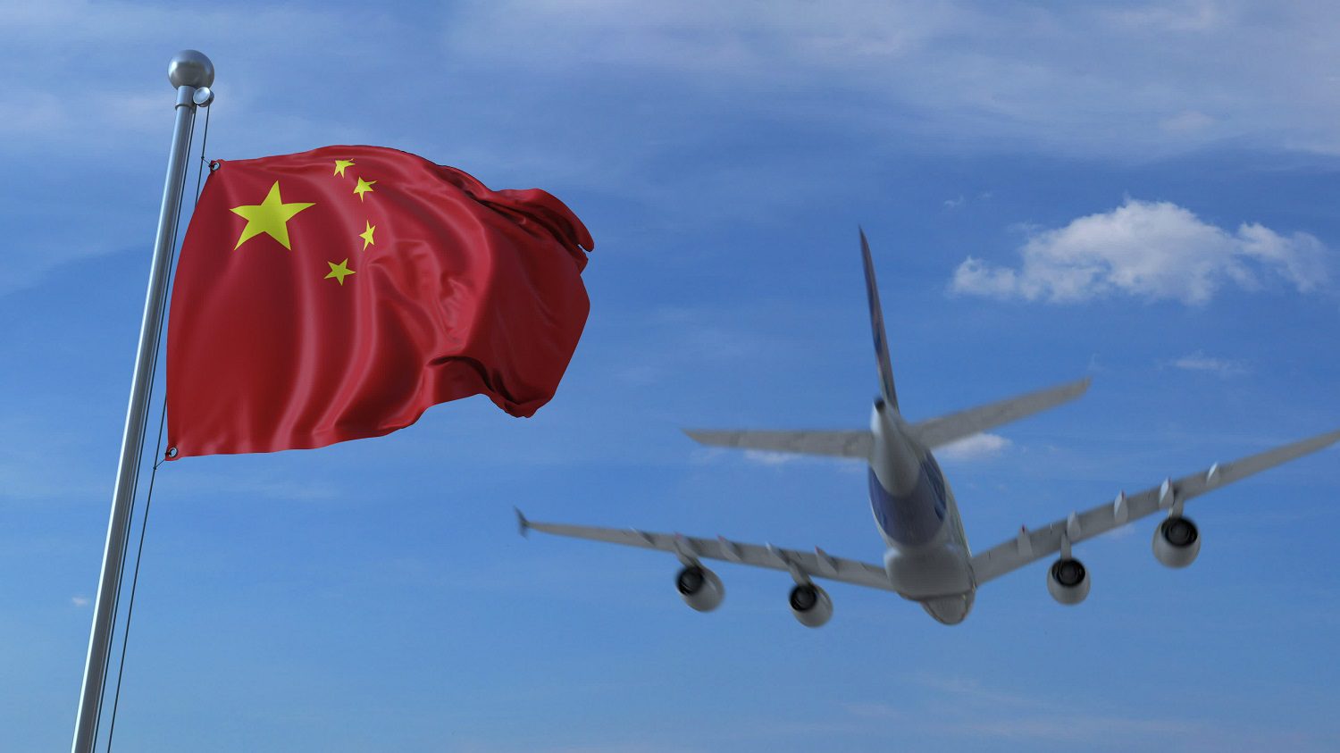 Un avión comercial vuela detrás de una bandera china ondeando al viento.