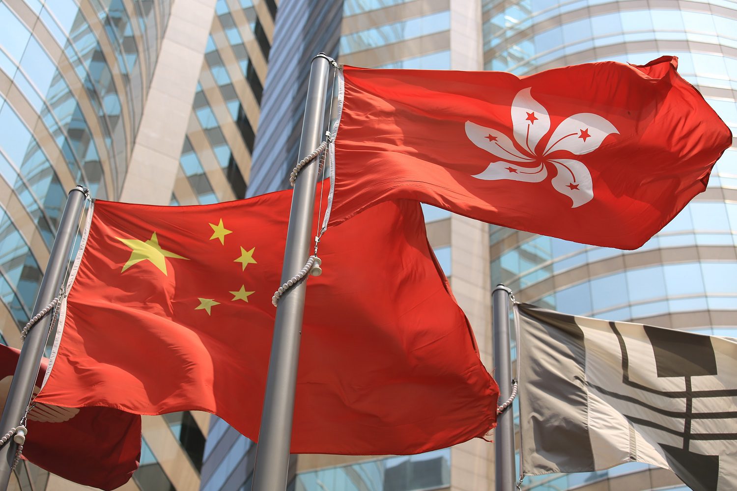 Las banderas de China y Hong Kong, izadas en astas y ondeando al viento.