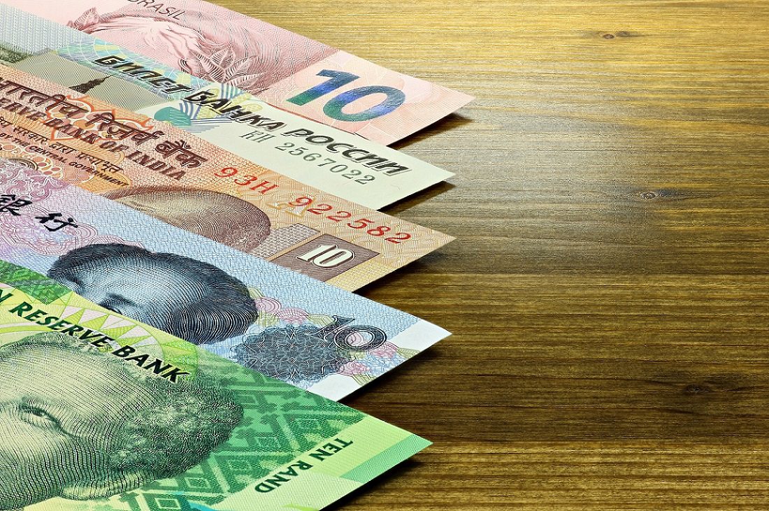 Los billetes de las cinco naciones BRICS descansan sobre una mesa de madera