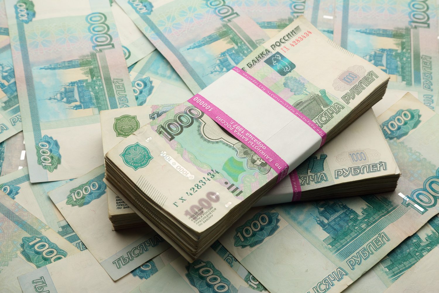 Dos fajos de billetes de 1.000 rublos rusos encima de otro montón de billetes perdidos.