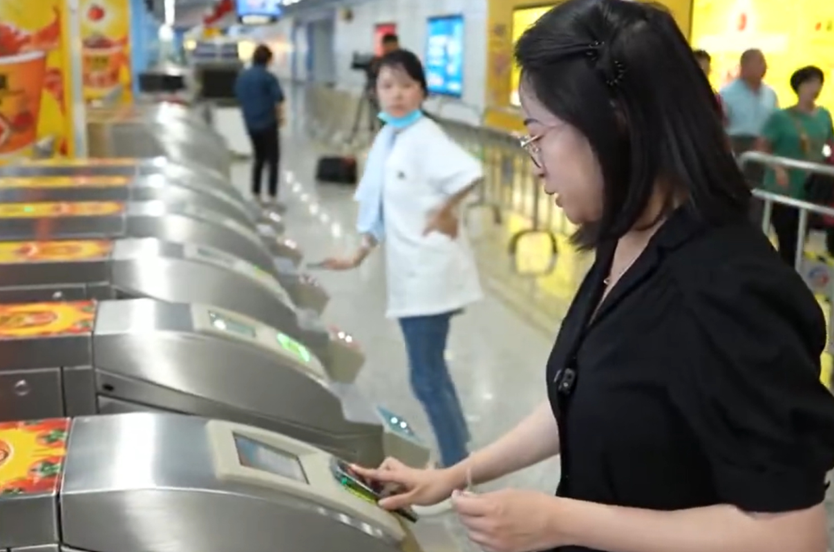 Un reportero de la televisión china utiliza una “billetera dura” basada en una tarjeta SIM en un teléfono inteligente apagado para pagar en la barrera del billete del metro.