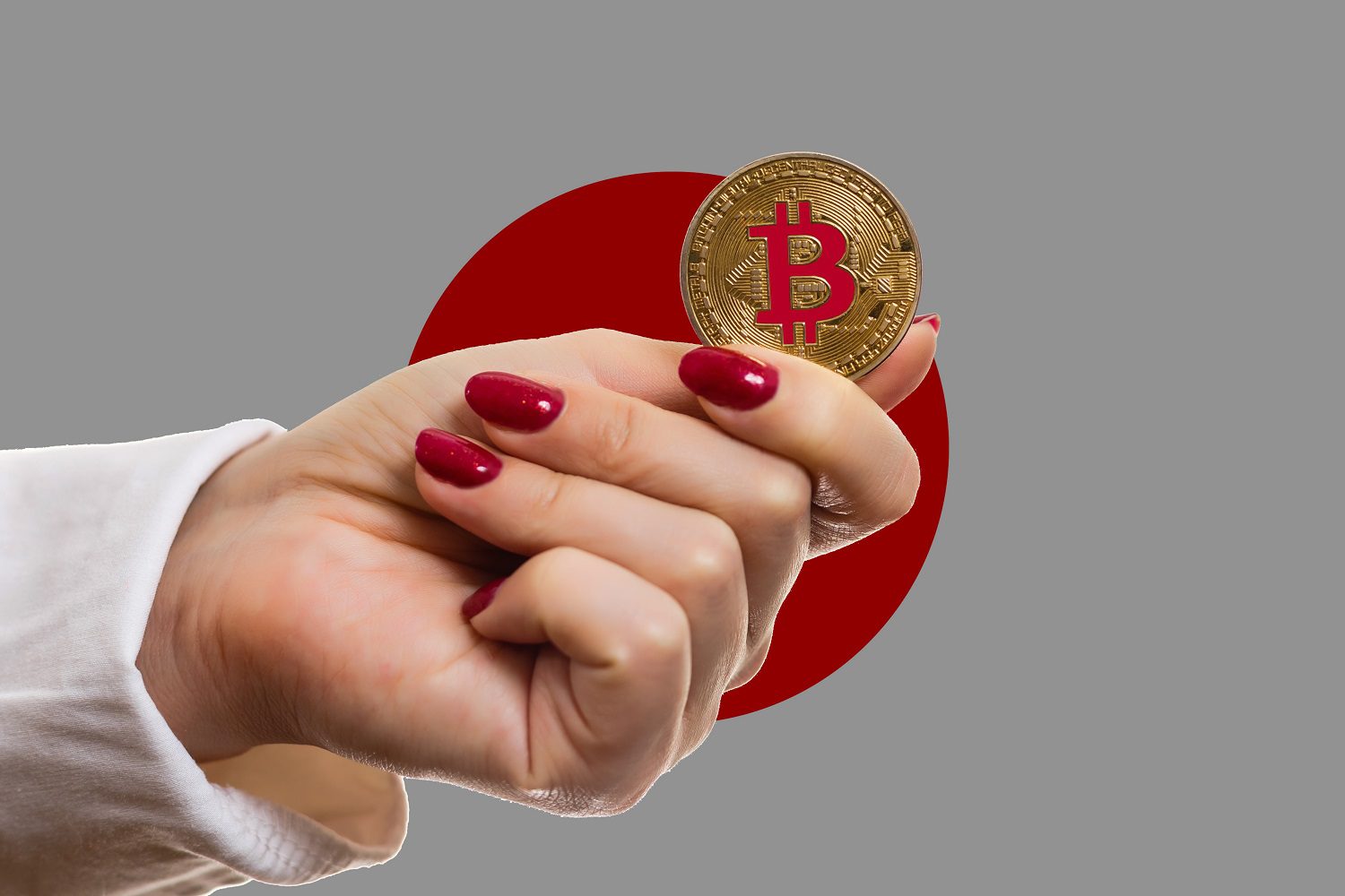 La mano de una mujer sostiene una ficha que representa Bitcoin contra el fondo de la bandera de Japón.