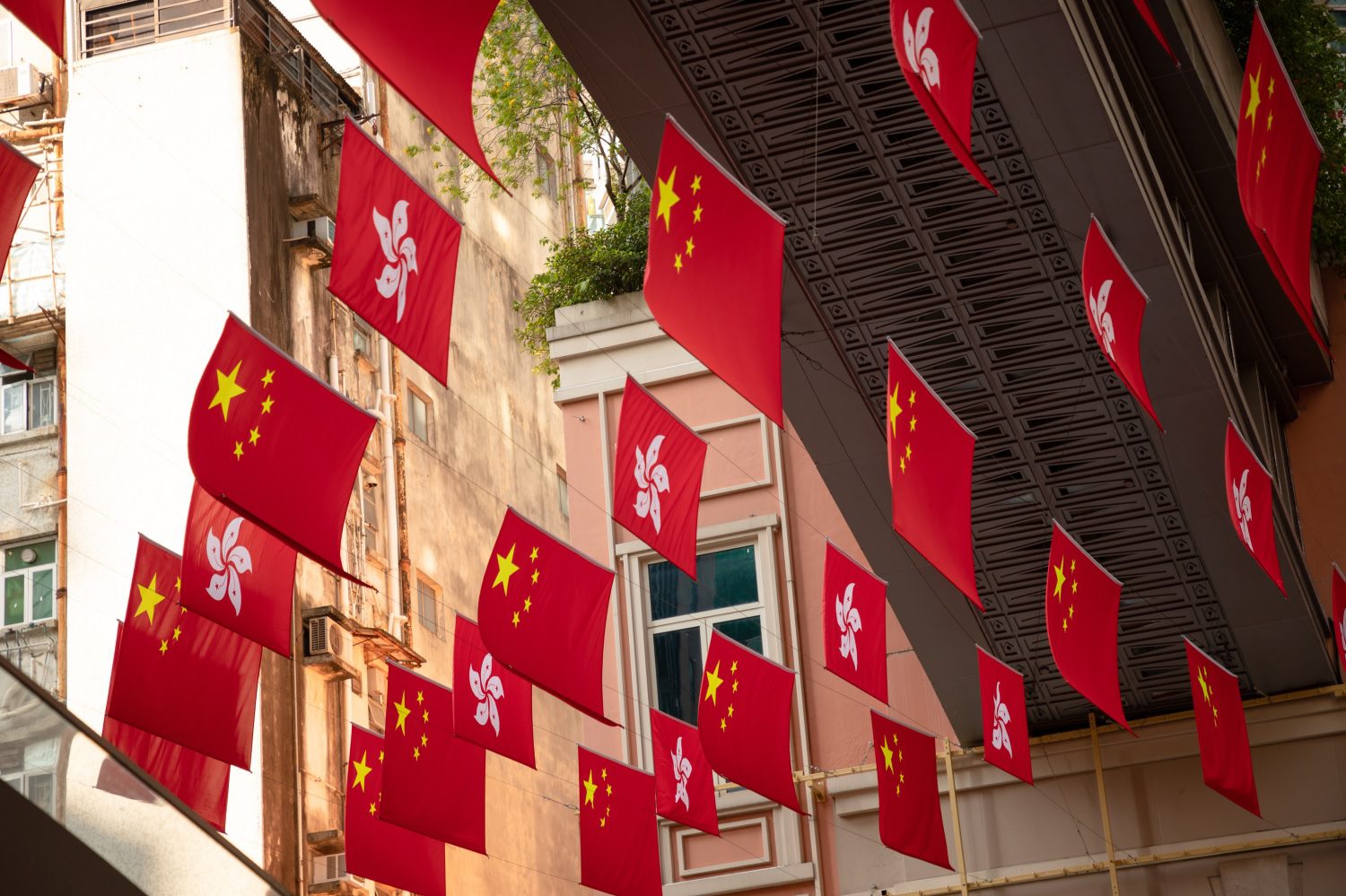 Banderas de la República Popular y de Hong Kong cuelgan en una calle pública.