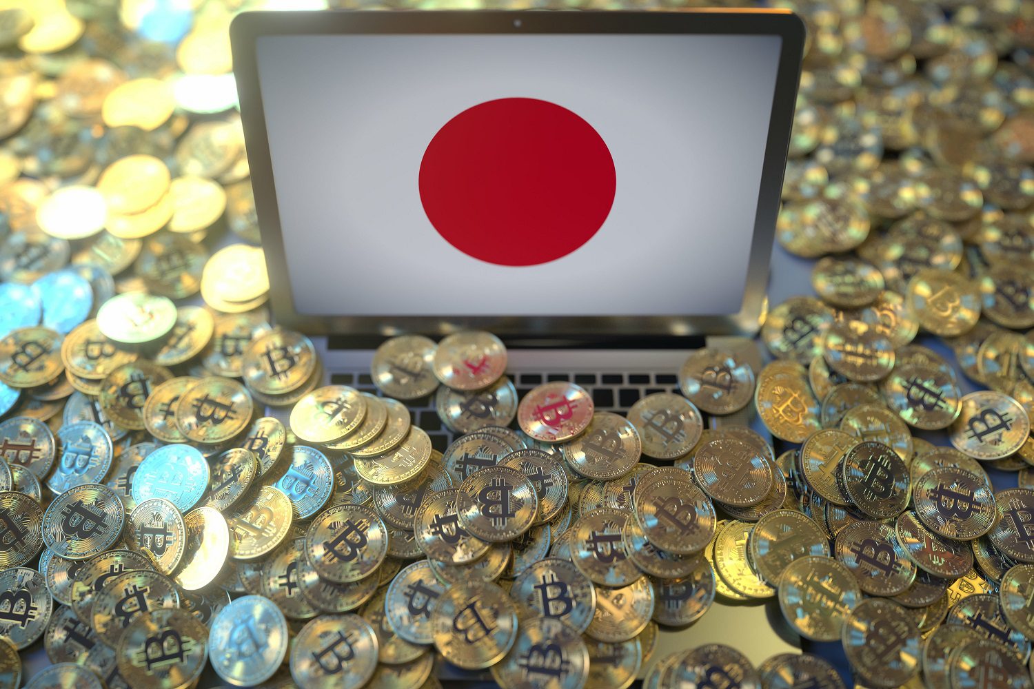 Una gran cantidad de fichas de metal de color dorado destinadas a representar Bitcoin se encuentran esparcidas alrededor de una computadora portátil cuya pantalla muestra la bandera japonesa.