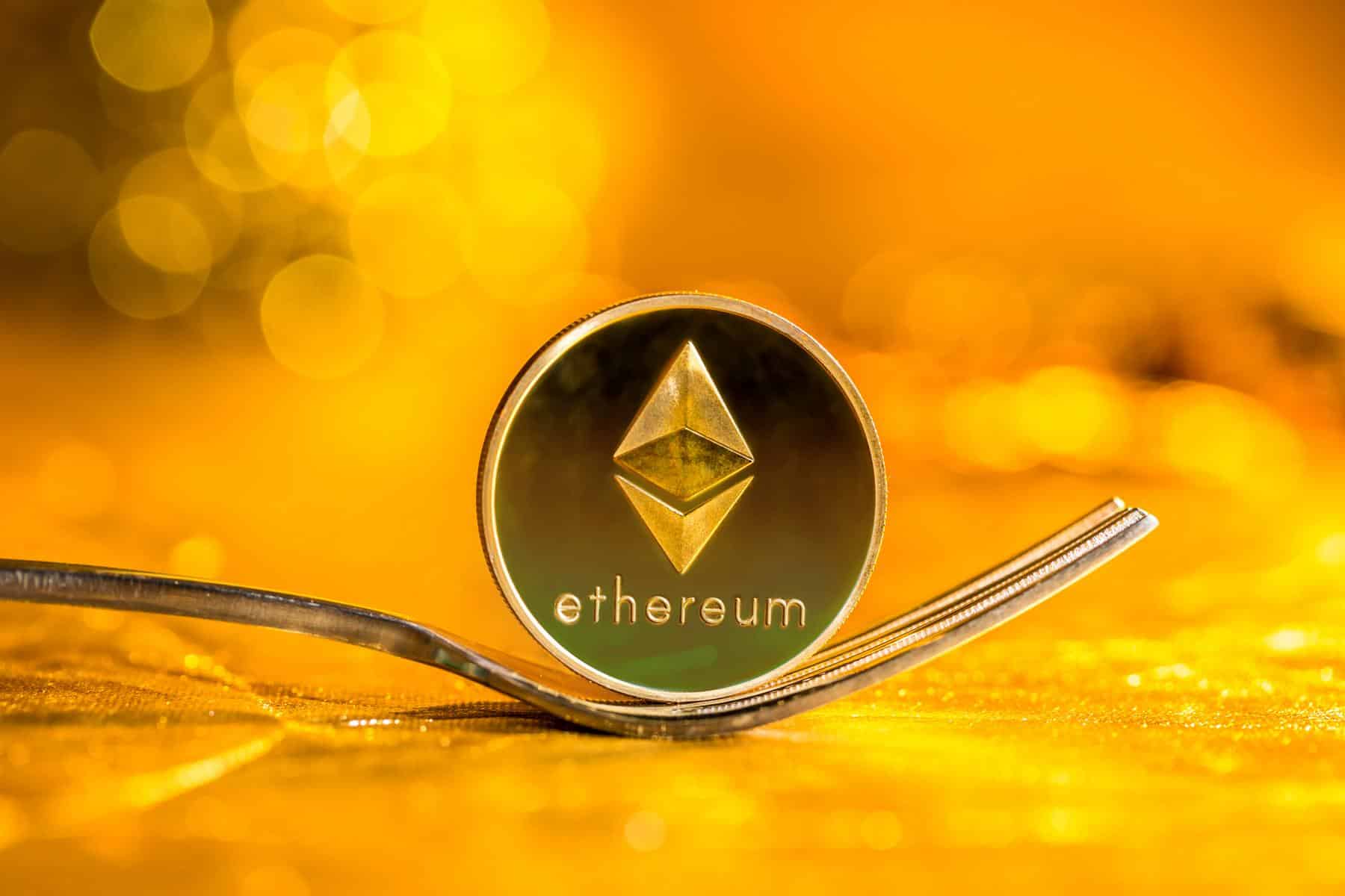 Ethereum-ETH-moneda-sostenida-por-tenedor-con-fondo-dorado